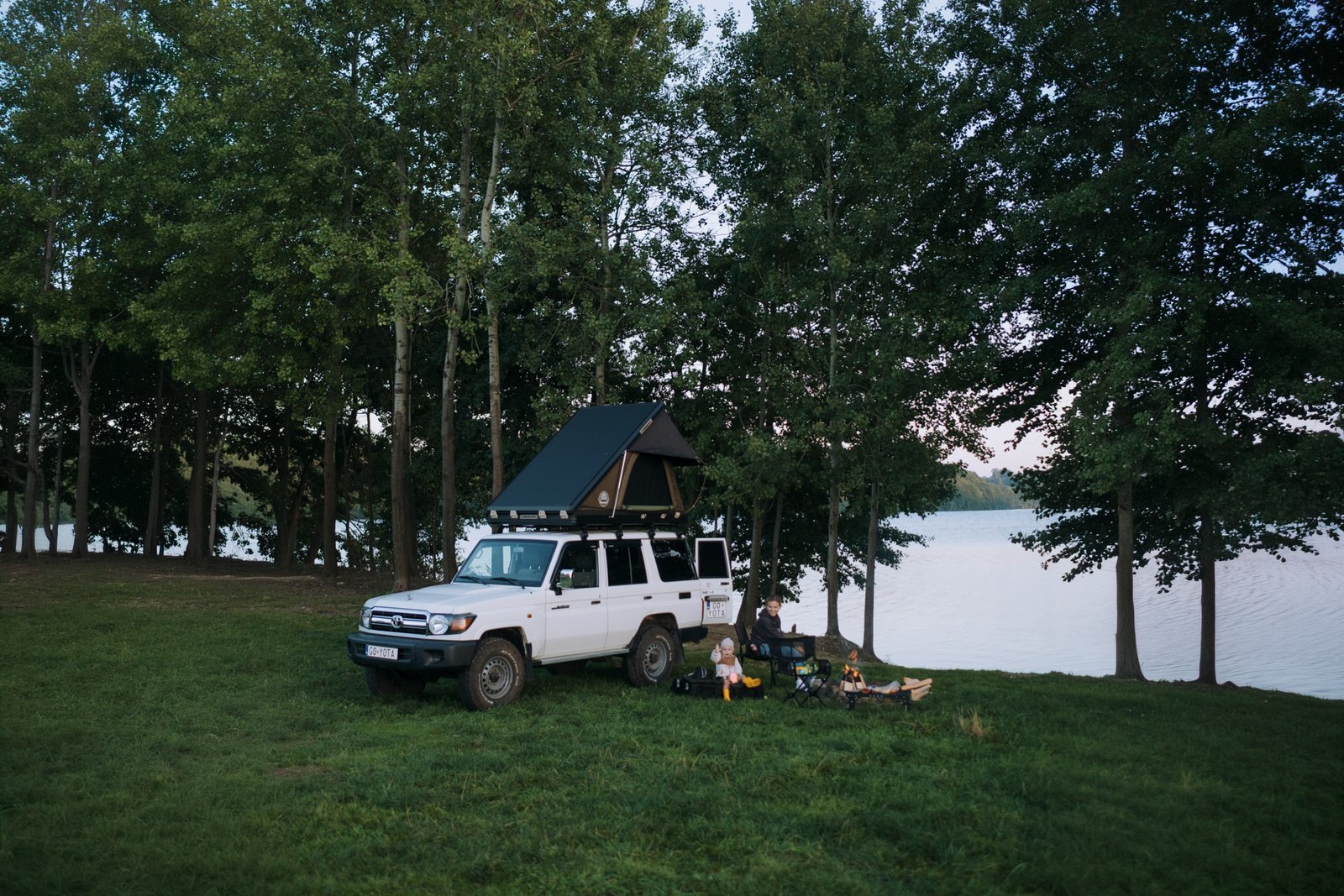 Land Cruiser 76 with the Hawk's Nest V2 Wide open on the roof, family camped by a lake in Kashubia