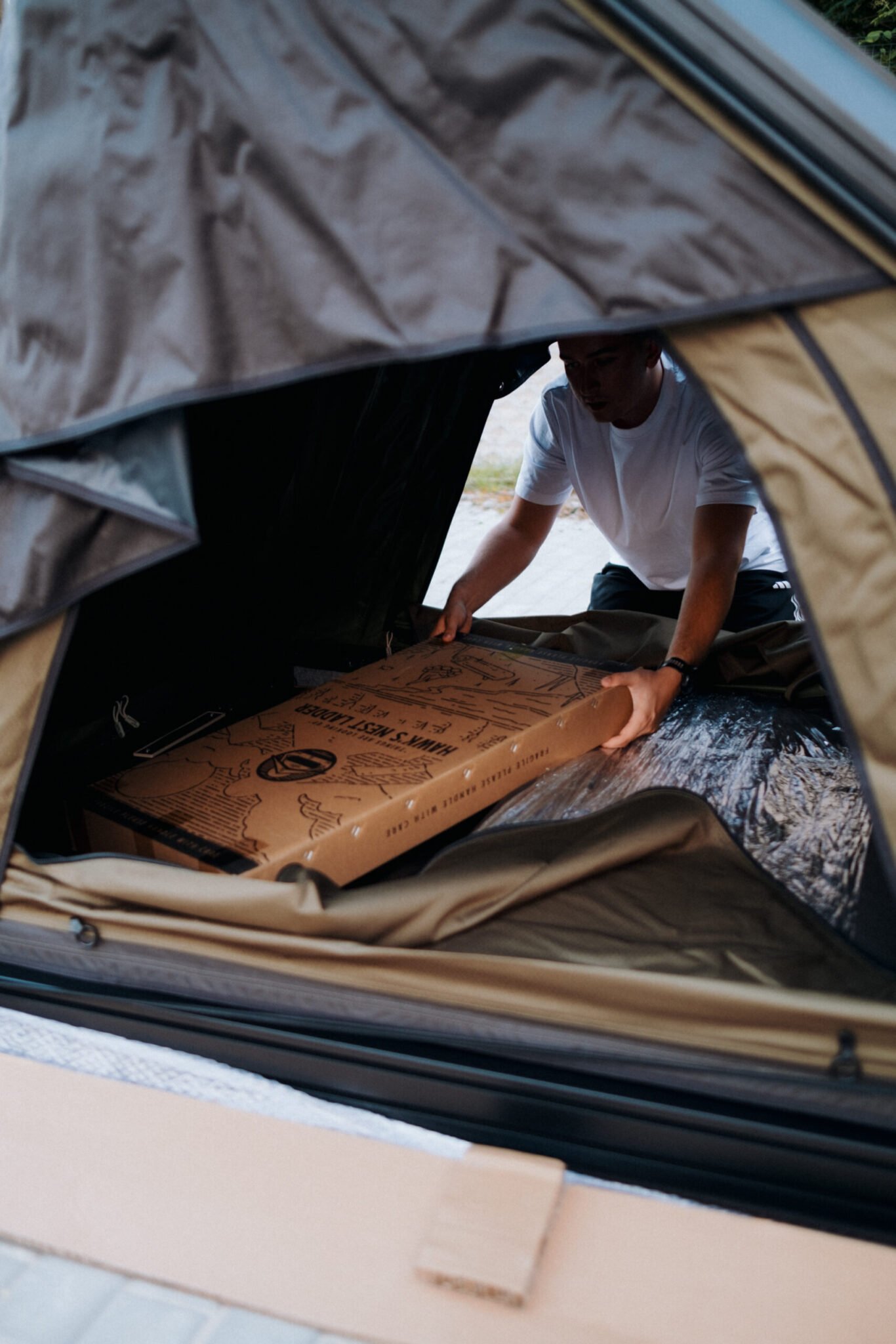 Unpacking a Hawk's Nest box inside the open rooftop tent