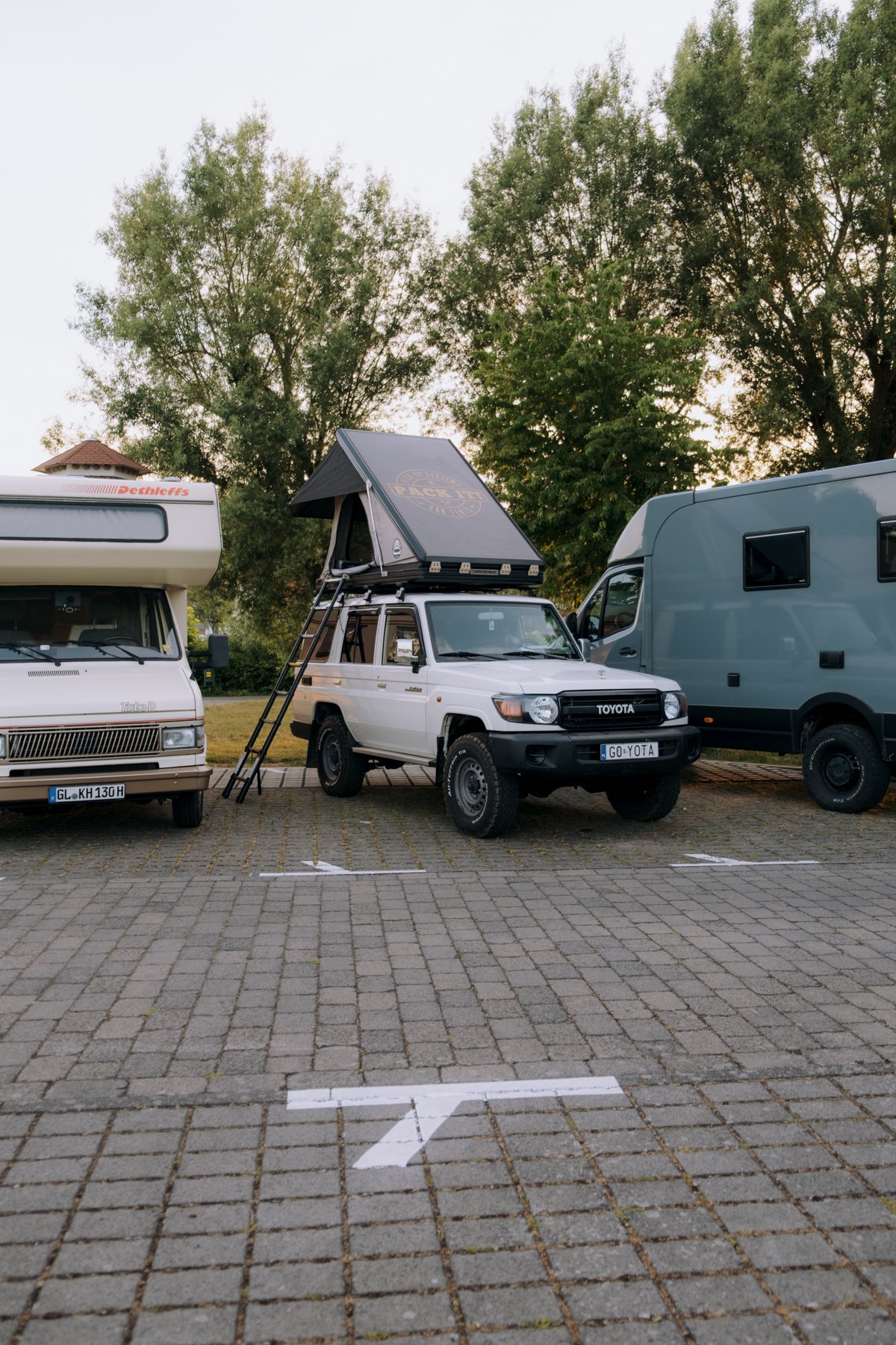 Land Cruiser 76 with a closed Standard Hawk's Nest V2 among campervans at the Abenteuer & Allrad camp area